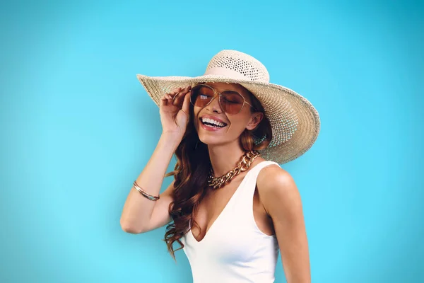 Portrait de belle jeune femme au chapeau élégant regardant la caméra tout en se tenant debout sur fond bleu — Photo