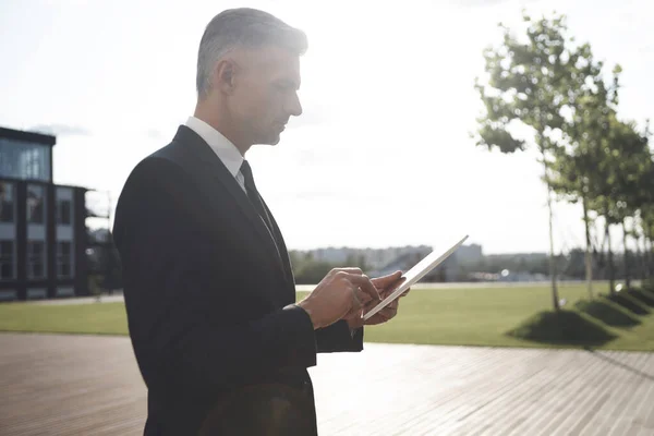 Confident mature businessman holding digital tablet while standing outdoors — Stock Photo, Image