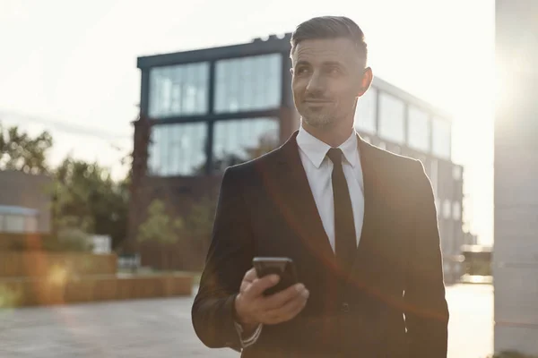 Ofis binasının yanında dururken elinde cep telefonu tutan kendinden emin bir iş adamı. — Stok fotoğraf