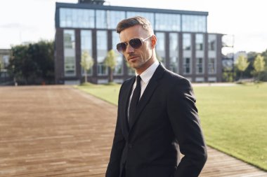 Ofis binasının önünde duran kendinden emin bir iş adamı.