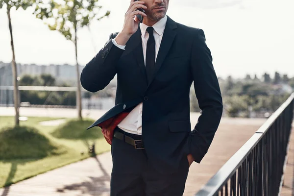 一个自信成熟的商人站在户外用手机交谈 — 图库照片