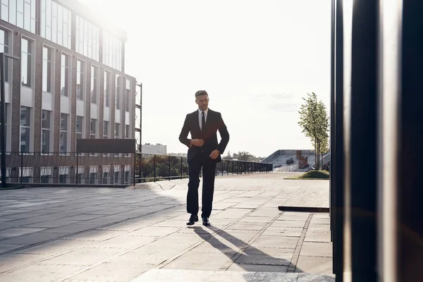 Kendine güvenen olgun iş adamı ofis binasının yakınında yürüyor. — Stok fotoğraf