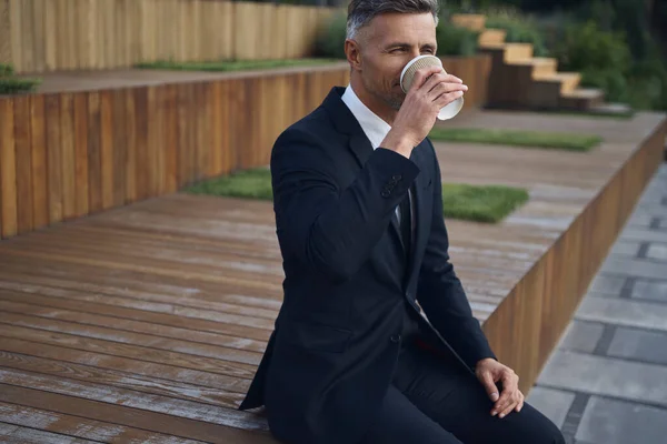 Zrelaksowany Dojrzały Biznesmen Pijący Kawę Siedząc Świeżym Powietrzu Pobliżu Biurowca — Zdjęcie stockowe