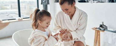 Anne ve kızı sabahları çalışırken gülümsüyor ve el kremi kullanıyor.