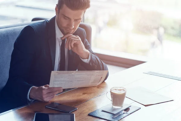 Guapo joven hombre de negocios en traje completo menú de lectura mientras está sentado en el restaurante — Foto de Stock