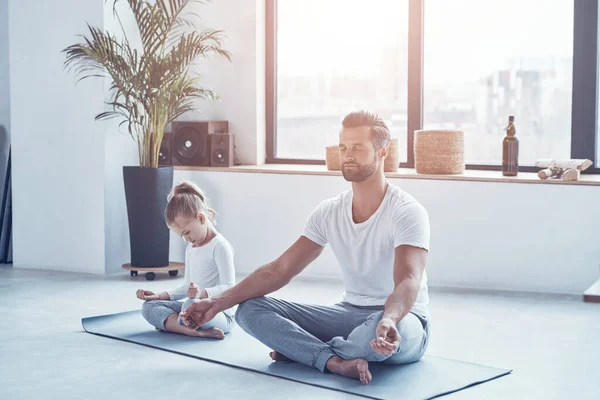 Padre e figlia che fanno yoga mentre sono seduti in posizione di loto a casa — Foto Stock