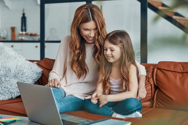 Jong mooi moeder en haar kleine dochter bonding samen en glimlachen terwijl met behulp van laptop thuis — Stockfoto
