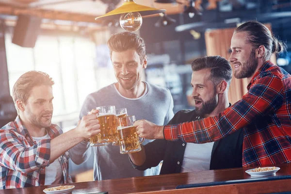 Groupe de jeunes hommes heureux dans des vêtements décontractés griller les uns les autres avec de la bière — Photo