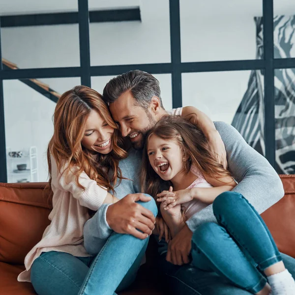 Felice giovane famiglia con bambina età prescolare sorridente mentre si legano insieme a casa — Foto Stock