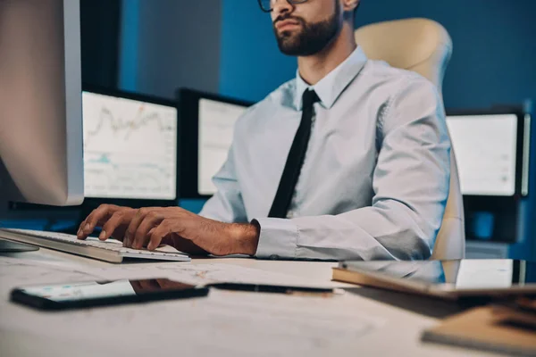 Gros plan d'un jeune homme qui travaille sur ordinateur tout en restant tard au bureau — Photo