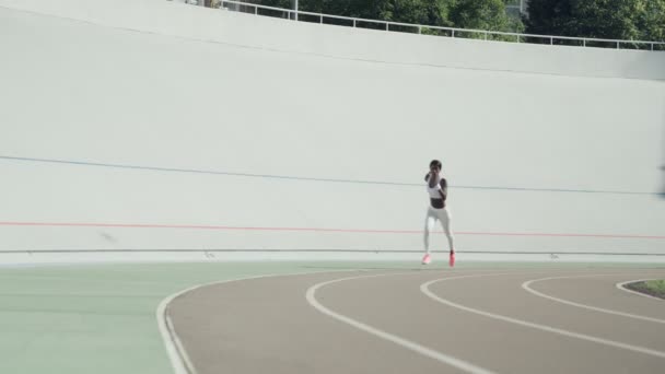 Mulher africana jovem confiante em roupas esportivas correndo na pista ao ar livre — Vídeo de Stock