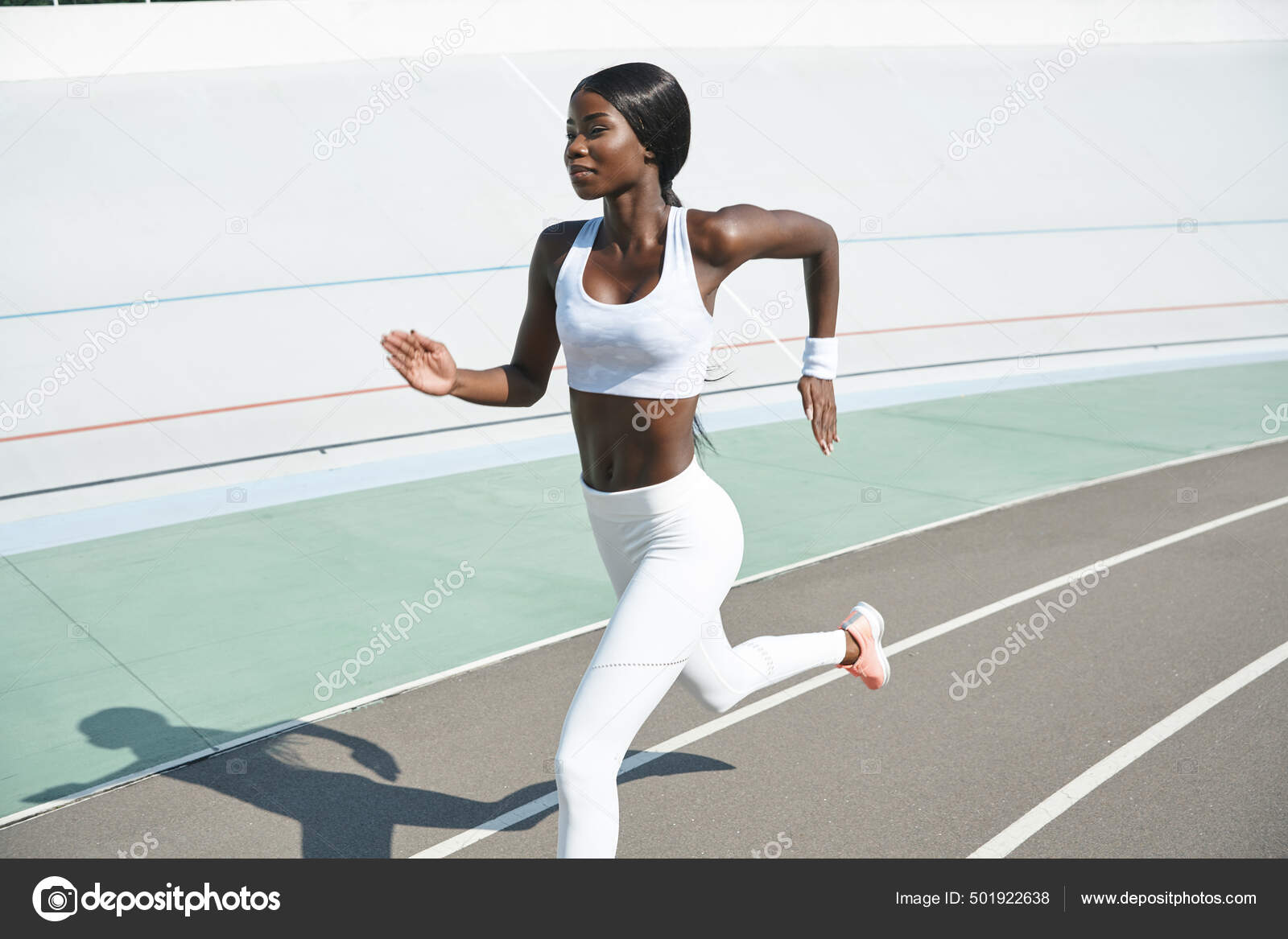 Belle jeune femme africaine en vetements de sport courir sur la piste en plein air Photo de stock par gstockstudio 501922638