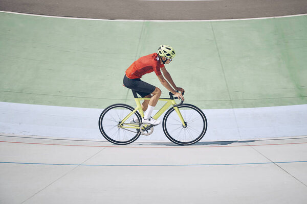 Top view of man in sports clothing cycling on track outdoors