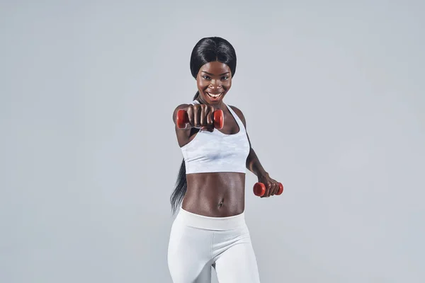Hermosa joven africana en ropa deportiva haciendo ejercicio con pesas —  Fotos de Stock