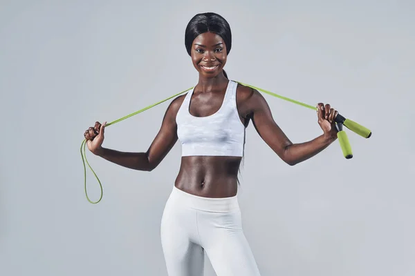 Sebevědomá mladá africká žena ve sportovním oblečení nesoucí švihadlo na ramenou — Stock fotografie