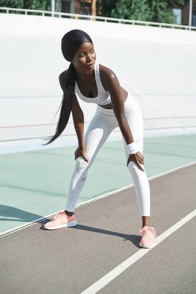 Krásná mladá africká žena ve sportovním oblečení relaxační po tréninku při stání venku — Stock fotografie