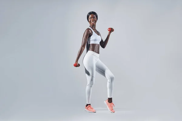Hermosa joven africana en ropa deportiva haciendo ejercicio con pesas — Foto de Stock