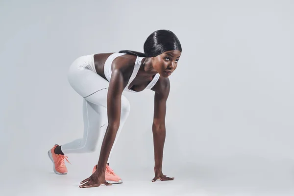 Belle jeune femme africaine debout à la position de départ et sur fond gris — Photo