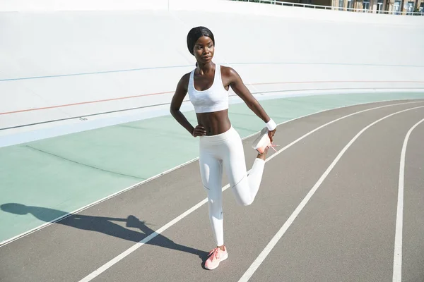 스포츠 의류를 입고 실외에서 스트레칭 운동을 하는 자신있는 젊은 아프리카 여성의 전체 길이 — 스톡 사진
