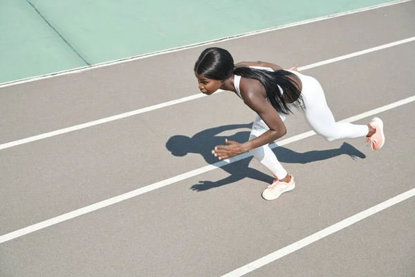 Draufsicht auf die schöne junge Afrikanerin in Sportkleidung, die im Freien auf der Strecke läuft — Stockfoto