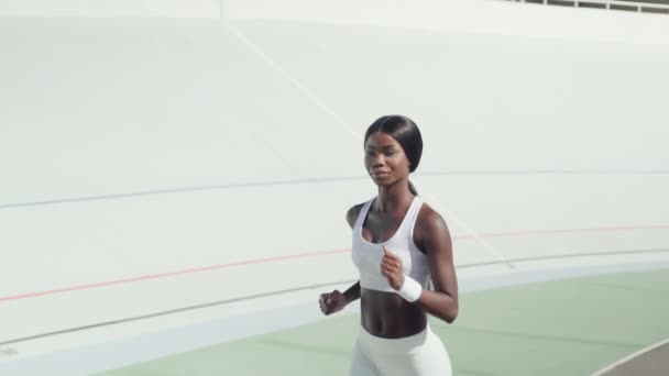 Mulher africana bonita em roupas esportivas correndo na pista ao ar livre — Vídeo de Stock