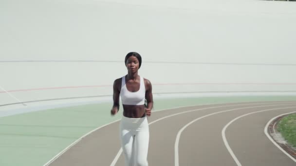 Mulher africana jovem confiante em roupas esportivas correndo na pista ao ar livre — Vídeo de Stock