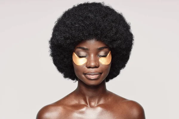 Portret van mooie jonge Afrikaanse vrouw met vlekken in de buurt van ogen staan tegen grijze achtergrond — Stockfoto