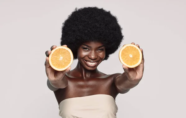 오렌지 조각을 들고 웃고 있는 아름다운 아프리카 여성의 모습 — 스톡 사진