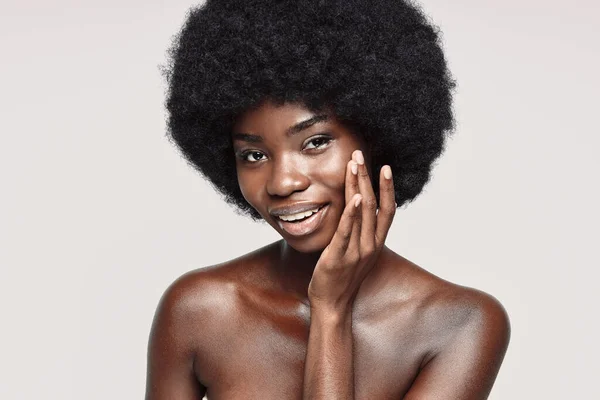 Портрет красивой молодой африканской женщины, касающейся лица и улыбающейся — стоковое фото