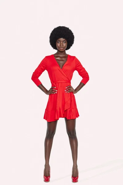 Full length of beautiful young African woman in red dress standing against gray background — Stock Photo, Image