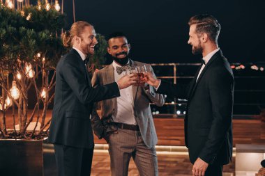 Takım elbiseli üç yakışıklı adam viski içip eğlenirken iletişim kuruyor.