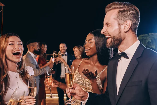 Grupo de gente hermosa en ropa formal comunicándose y sonriendo mientras pasa tiempo en una fiesta de lujo — Foto de Stock