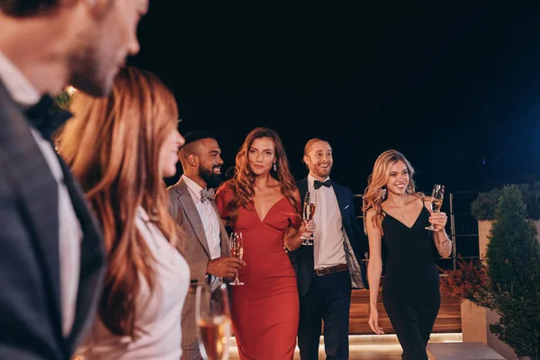 Gruppo di persone in abbigliamento formale che comunicano e sorridono mentre trascorrono del tempo alla festa di lusso — Foto Stock
