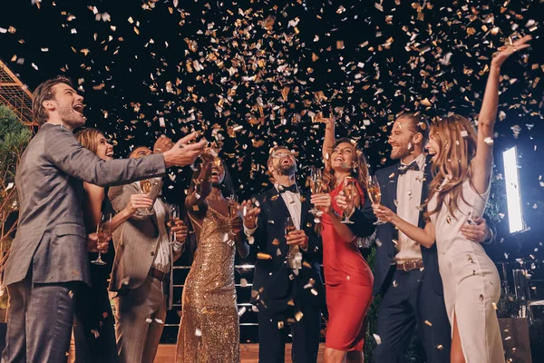 Gruppe schöner Menschen in Formalbekleidung amüsiert sich mit herumfliegendem Konfetti — Stockfoto