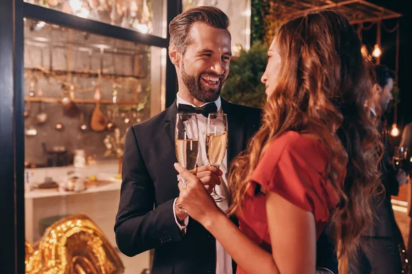 Hermosa pareja joven en tostadas de ropa formal con champán mientras pasa tiempo en una fiesta de lujo — Foto de Stock
