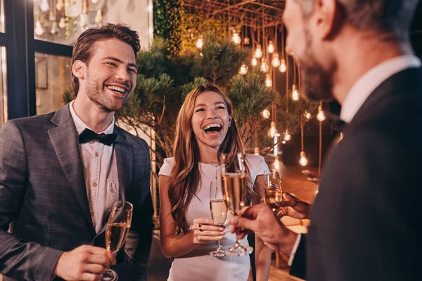 Grupo de personas en ropa formal comunicándose y sonriendo mientras pasan tiempo en una fiesta de lujo — Foto de Stock