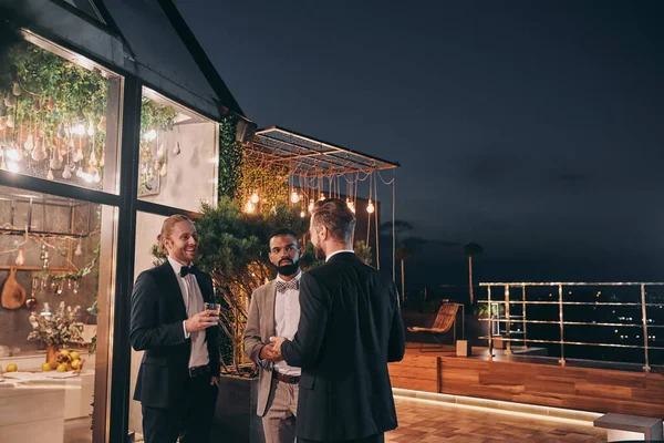 Tre välklädda män dricker whisky och kommunicerar medan de festar. — Stockfoto