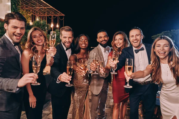 Gruppe von Menschen in Formalbekleidung prostet mit Champagner zu und lächelt, während sie Zeit auf einer Luxusparty verbringt — Stockfoto