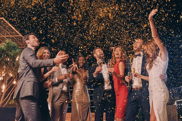 Gruppe schöner Menschen in Formalbekleidung amüsiert sich mit herumfliegendem Konfetti — Stockfoto