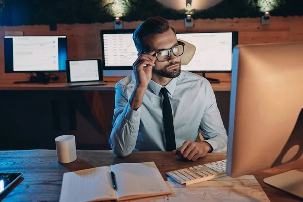 Selbstbewusster junger Mann arbeitet am Computer und bleibt spät im Büro — Stockfoto