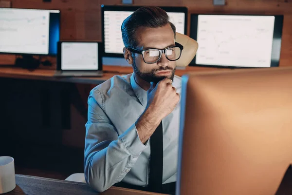 遅くまでオフィスにいる間にコンピュータに取り組んでいる若い男を自信を持って — ストック写真