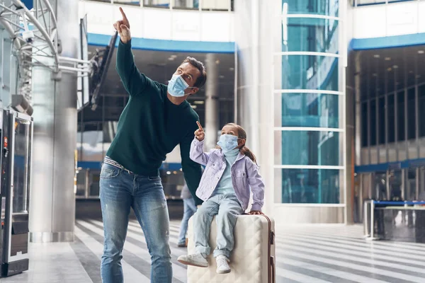 공항 터미널에서 탑승하기 위해 얼굴을 보호하는 마스크를 쓰고 있는 젊은 아버지와 딸 — 스톡 사진