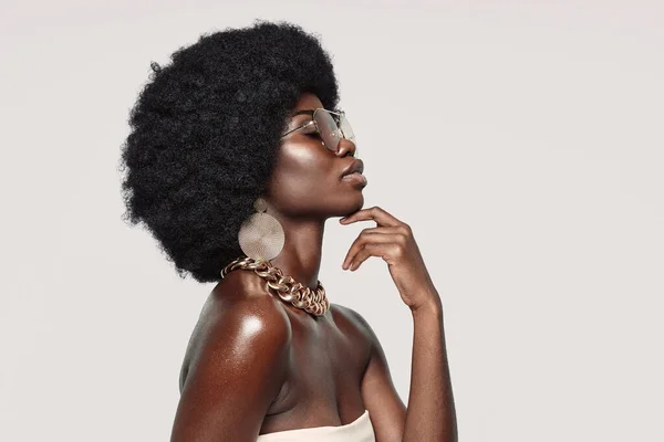 Zijaanzicht van mooie jonge Afrikaanse vrouw in gouden sieraden houden ogen gesloten en ontroerend gezicht — Stockfoto