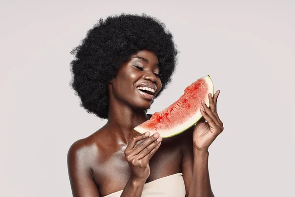 Портрет красивой молодой африканской женщины, держащей кусок арбуза и улыбающейся — стоковое фото
