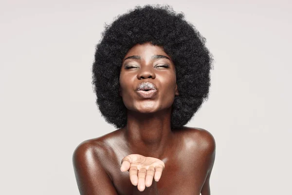 Retrato de una hermosa joven africana manteniendo los ojos cerrados y soplando un beso — Foto de Stock