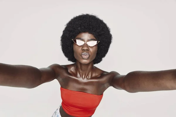 Gri arka planda dururken selfie çeken güzel bir Afrikalı kadın. — Stok fotoğraf