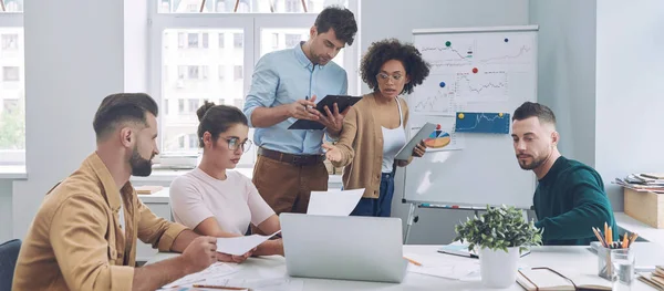 Gruppe selbstbewusster junger Leute in schicker Freizeitkleidung diskutiert Geschäfte, während sie sich im Büro treffen — Stockfoto