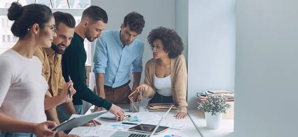 Equipo de negocios seguro que tiene una reunión rápida mientras está de pie cerca del escritorio de la oficina juntos — Foto de Stock