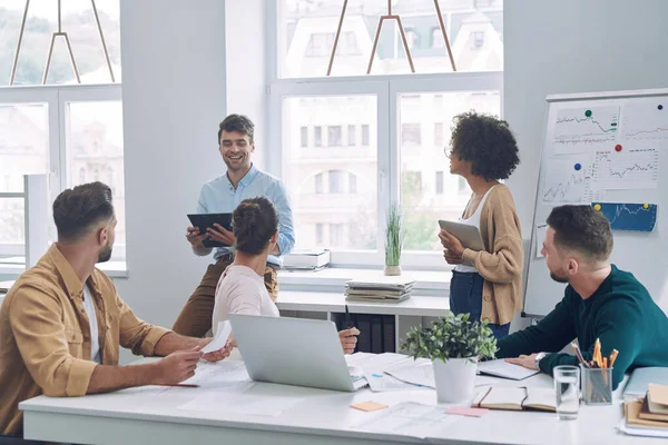 Gruppo di giovani fiduciosi in abbigliamento casual intelligente discutere di affari pur avendo riunione in ufficio — Foto Stock