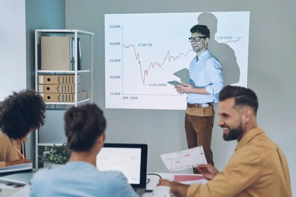 Groep van jonge moderne mensen in slimme casual wear analyseren van gegevens op projectiescherm in het kantoor — Stockfoto